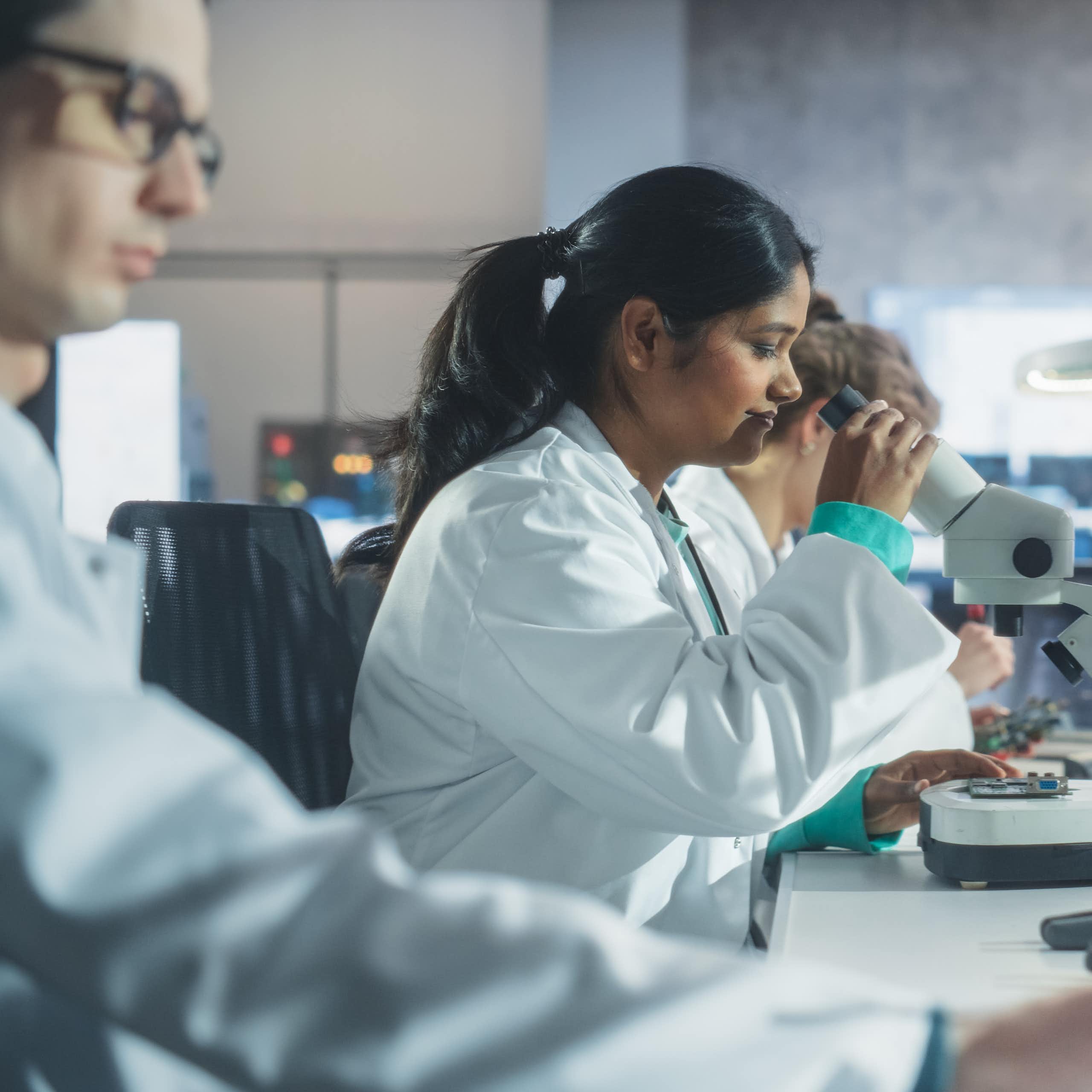 Un groupe de jeunes chercheurs portant le sarrau blanc, dans un laboratoire