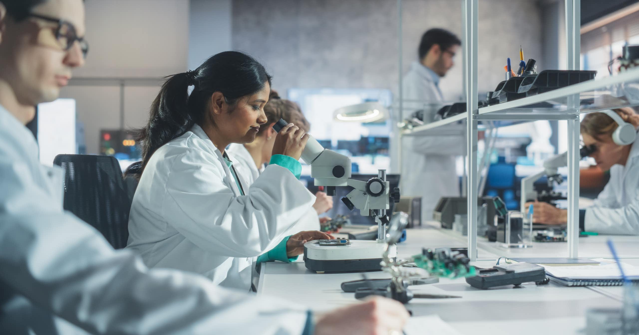 Un groupe de jeunes chercheurs portant le sarrau blanc, dans un laboratoire