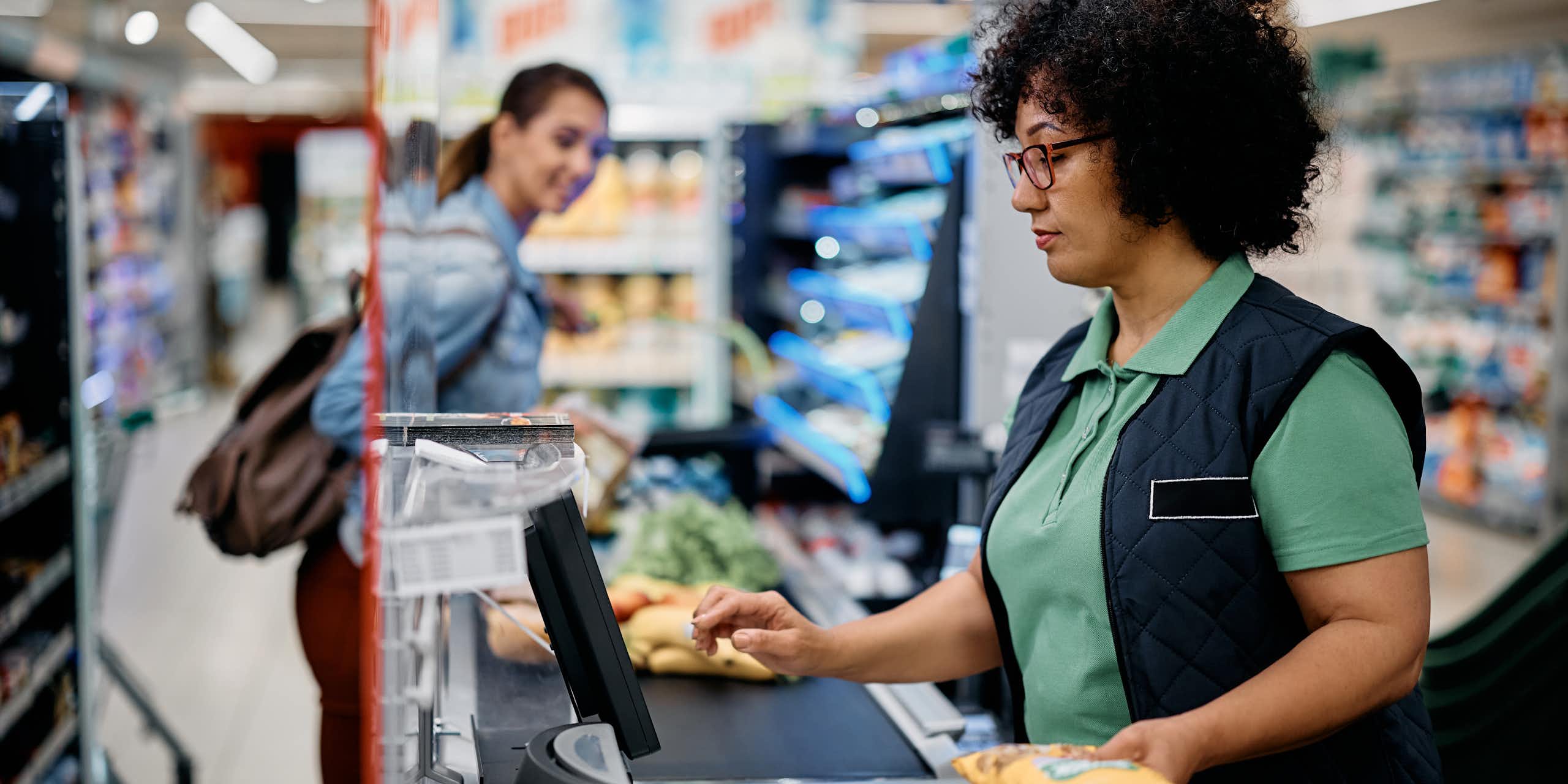 Une femme scanne des produits dans une caisse de supermarché