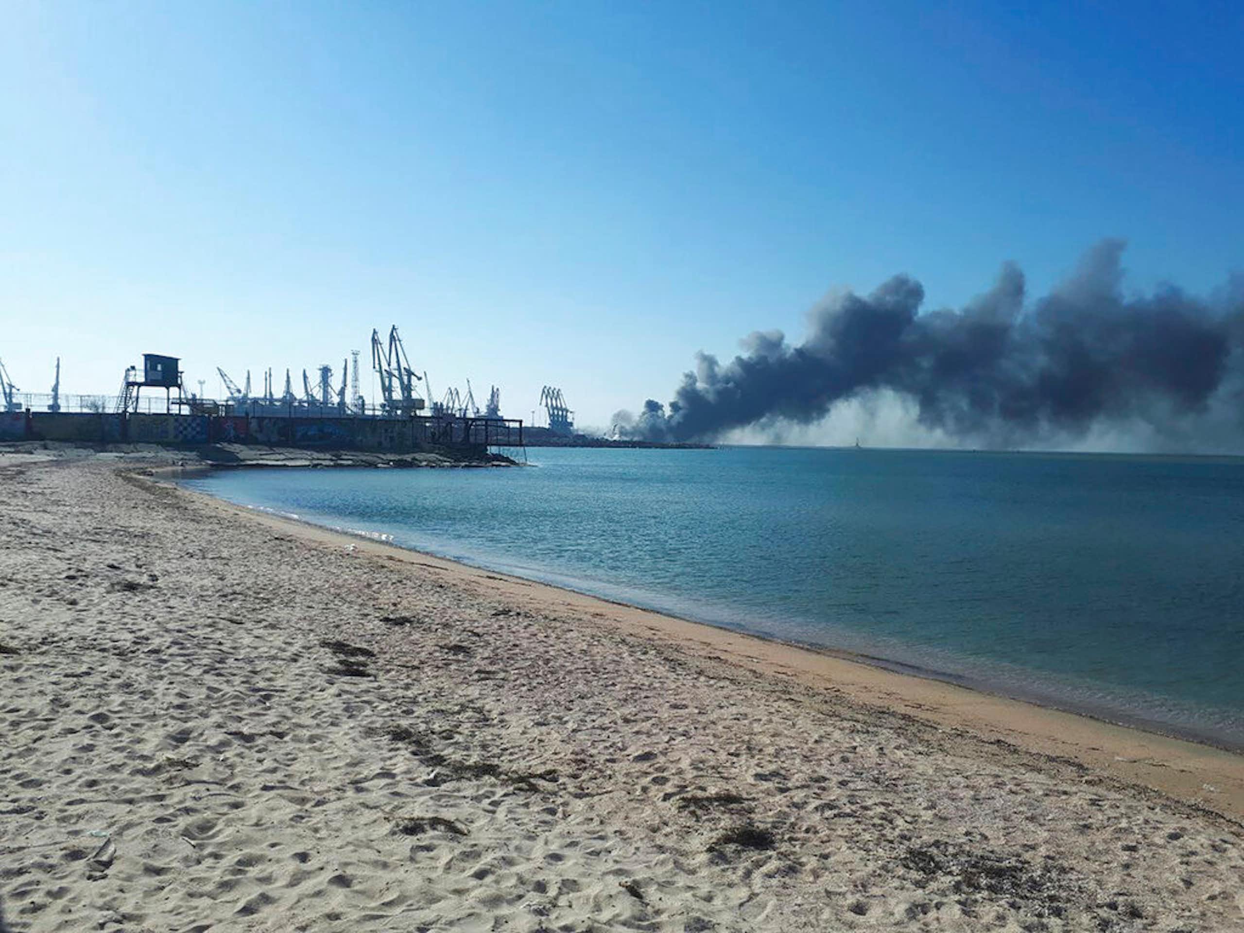 Smoke billows from a ship in the sea.