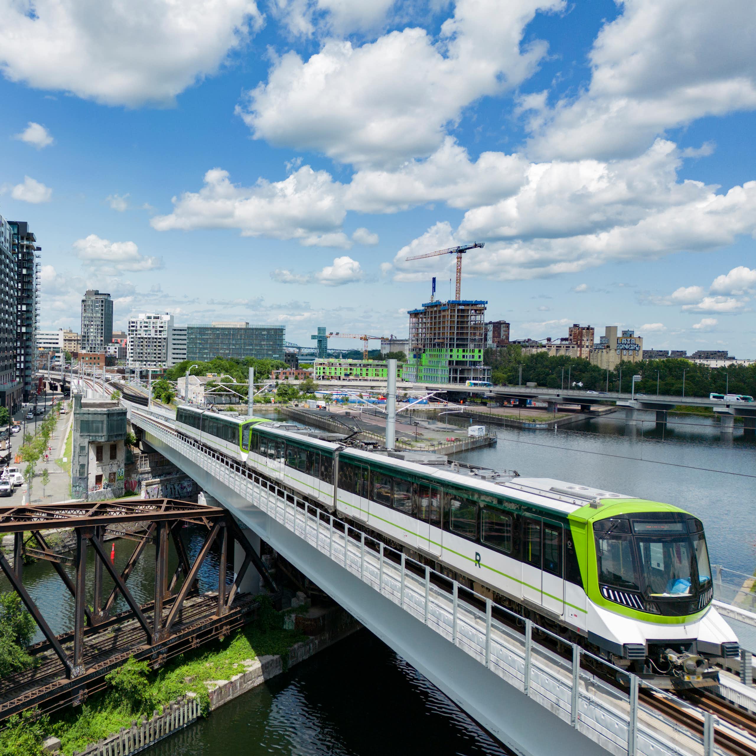 A light rail train riding a trail track over a bridge that is above a wide river
