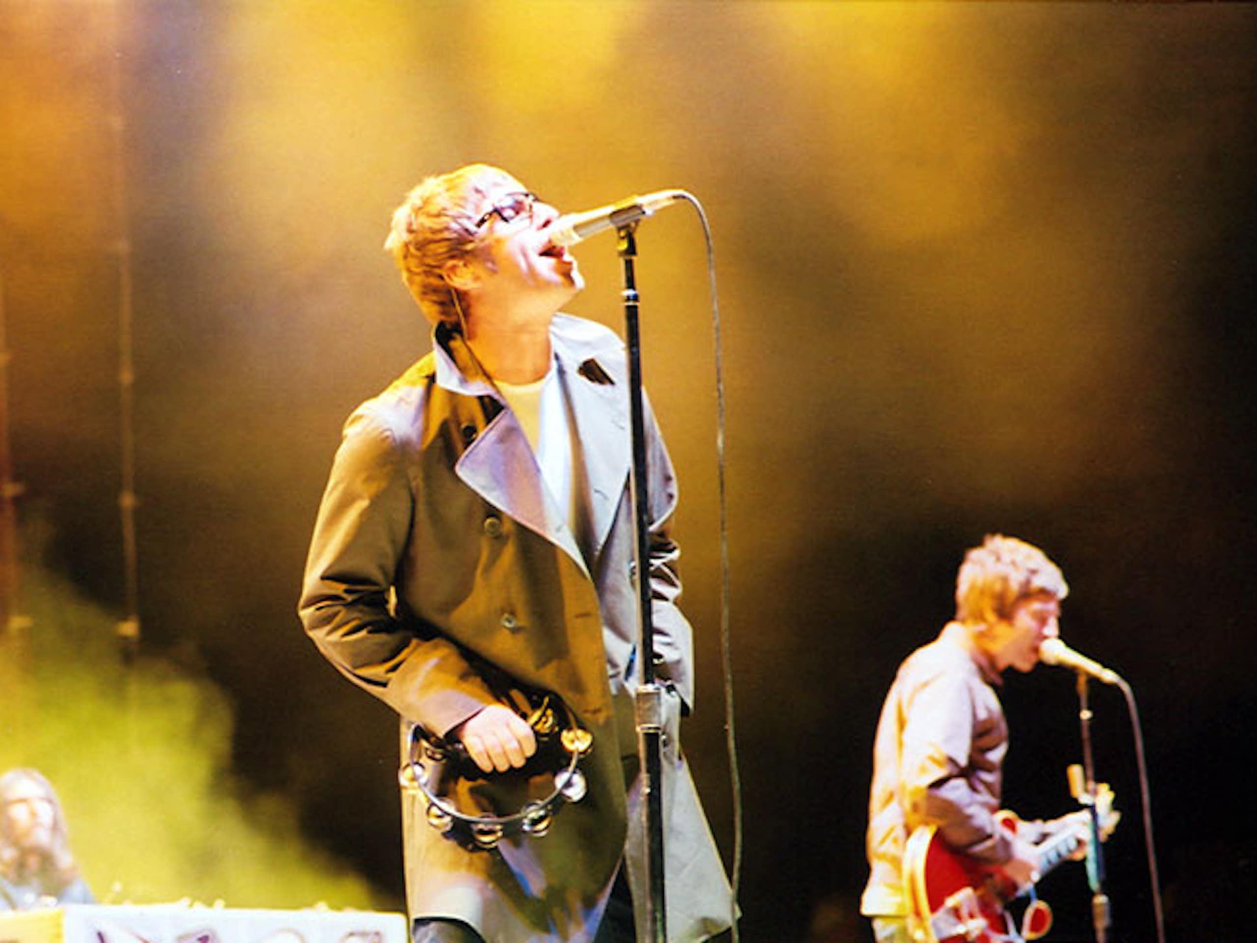 Two musicians on a stage, one singing, the other playing guitar.