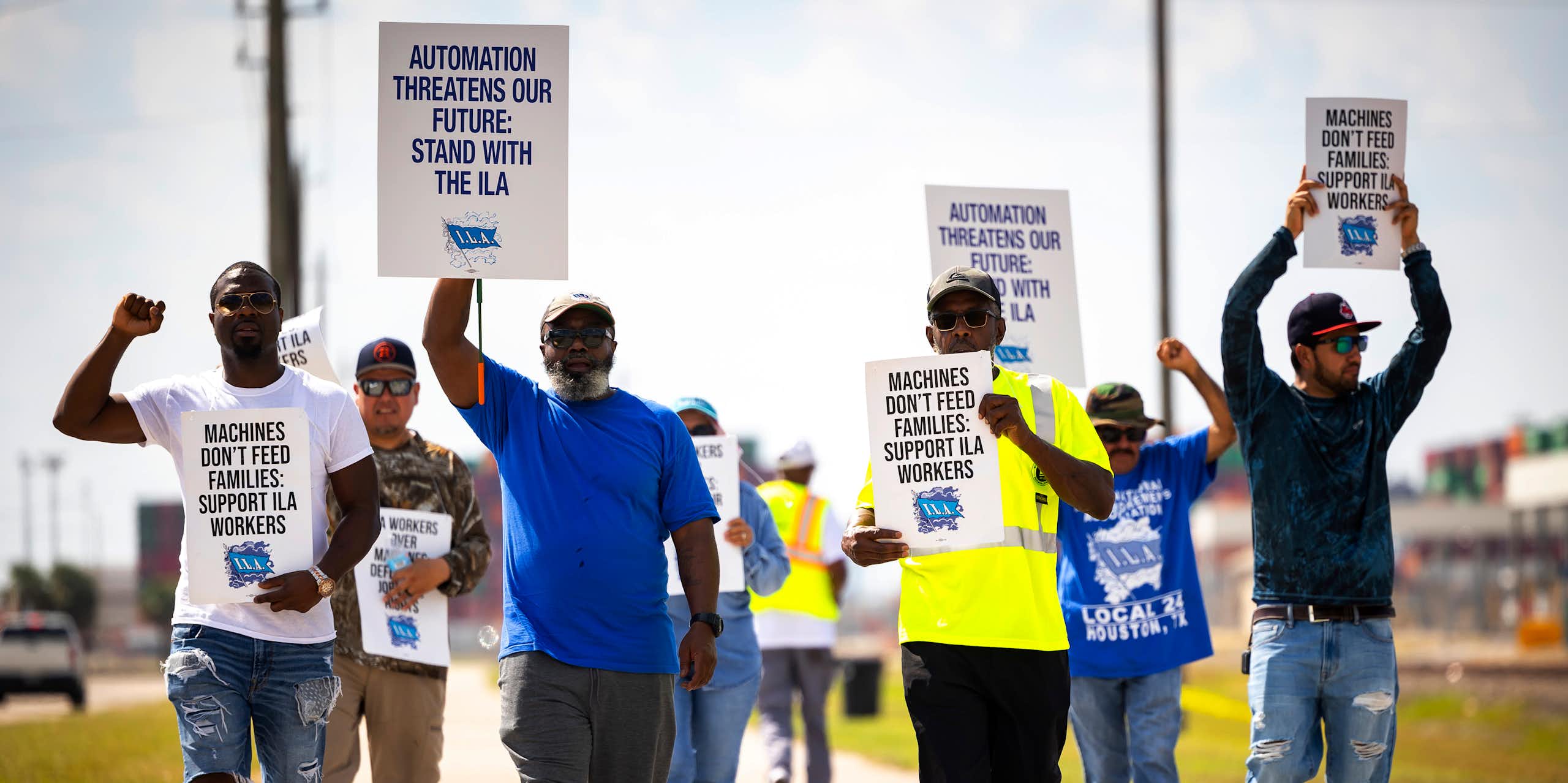 A group of men hold protest signs protesting against automation replacing workers