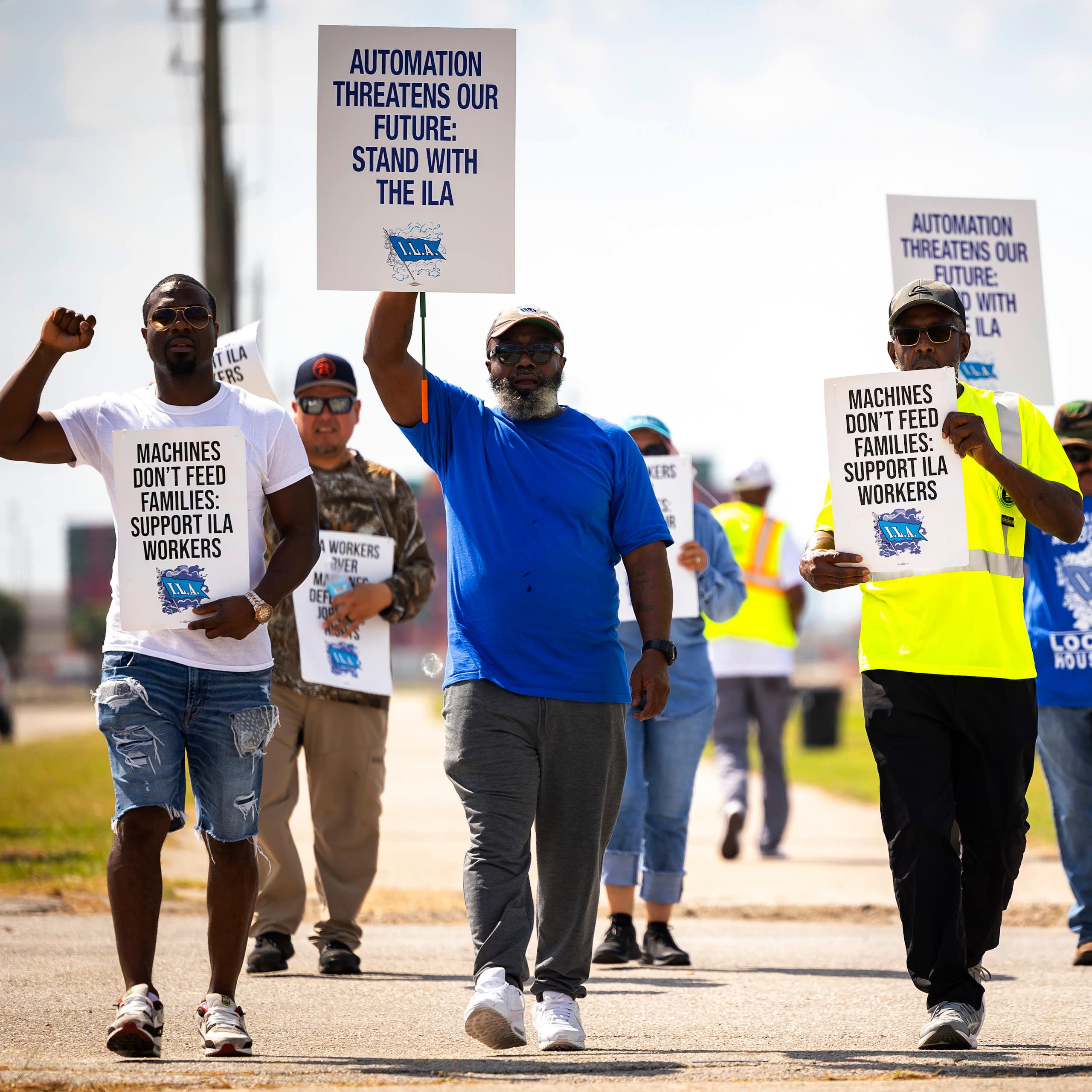 A group of men hold protest signs protesting against automation replacing workers