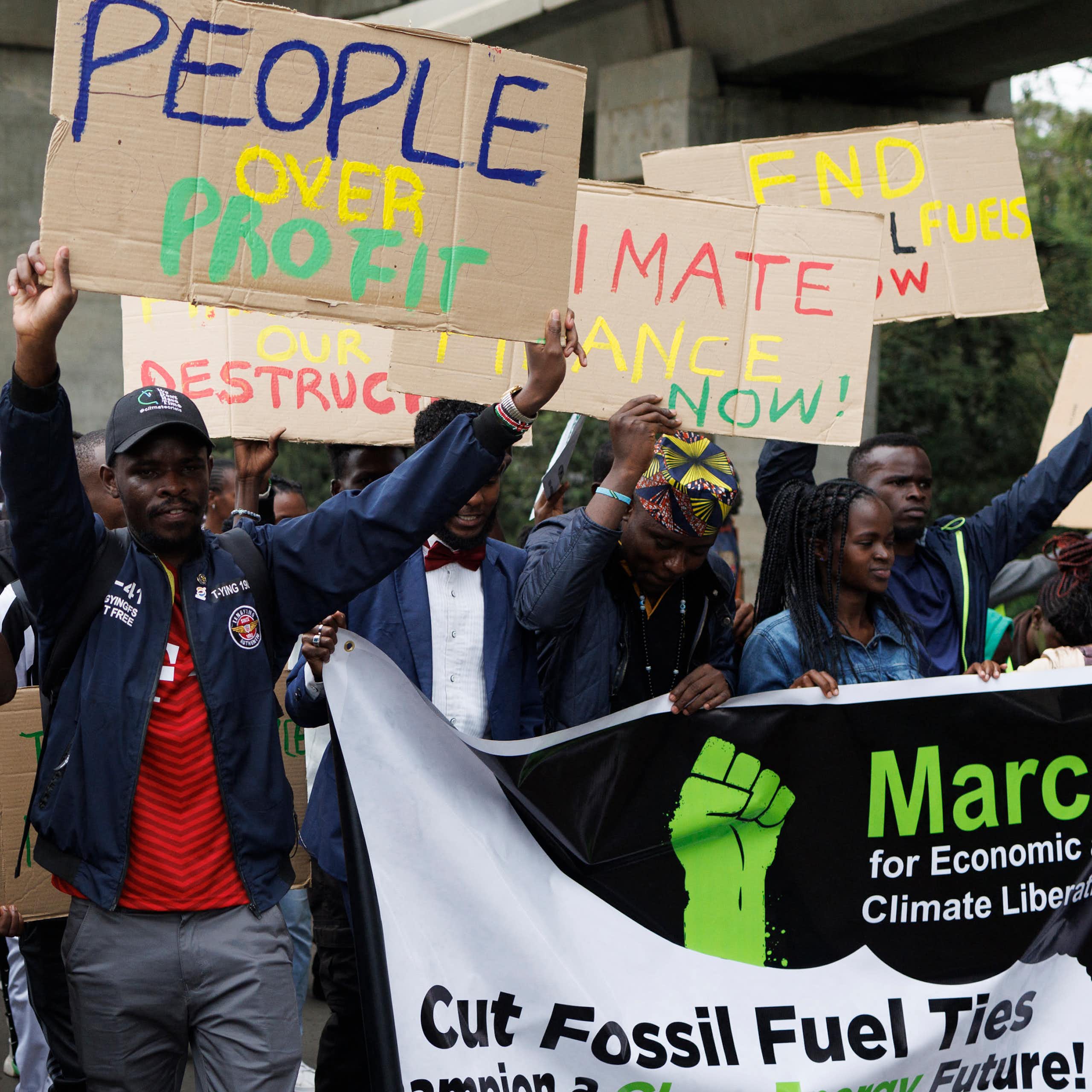 Protestors march with placards that say End Fossil Fuels, AFDB stop displacing our communities, Climate Finance Now, Cut Fossil Fuel Ties, and People over Profit
