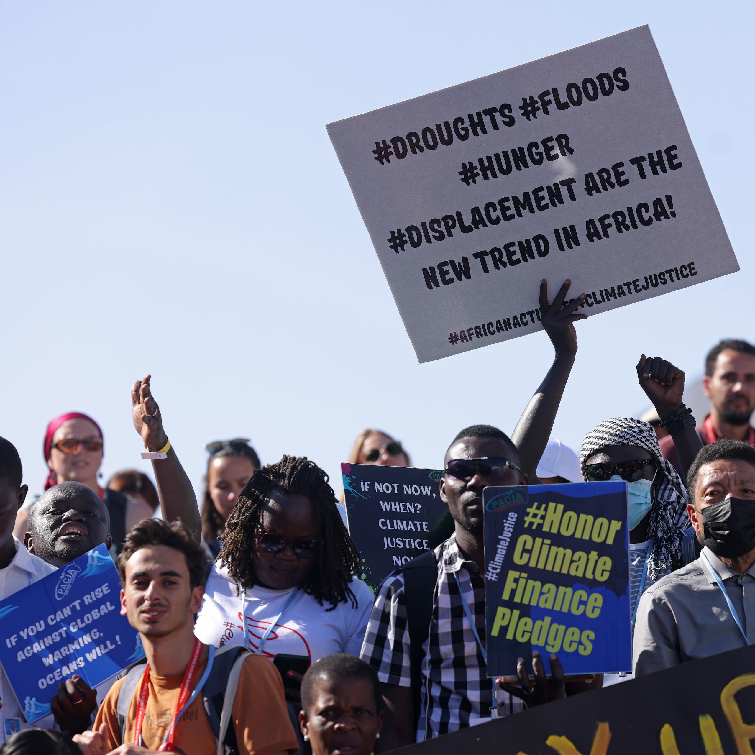 A protest of about 100 people holding placards stating "Honor climate finance pledges" and "Droughts, Floods, Hunger, Displacement are the new trend in Africa!"