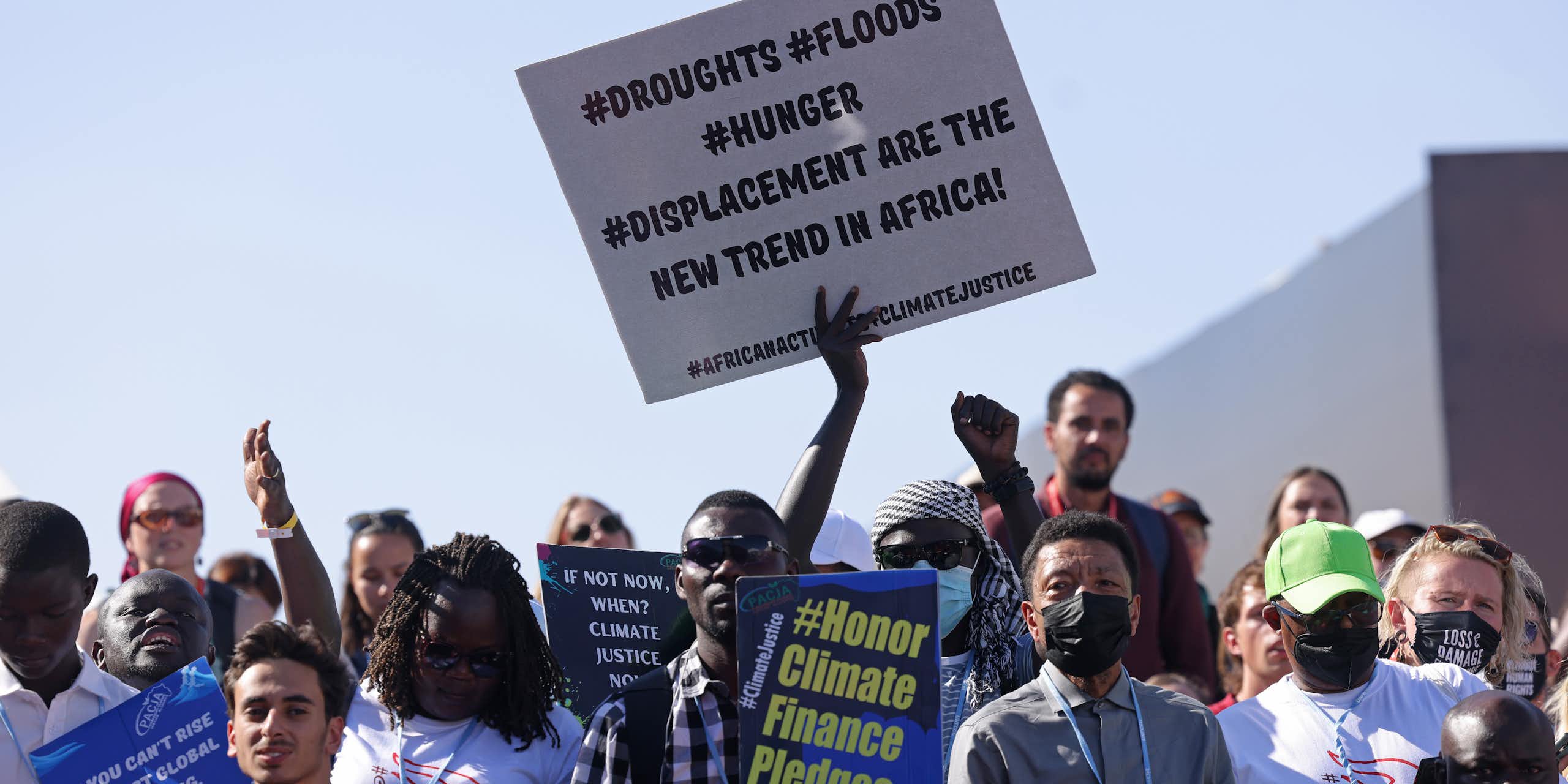 A protest of about 100 people holding placards stating "Honor climate finance pledges" and "Droughts, Floods, Hunger, Displacement are the new trend in Africa!"