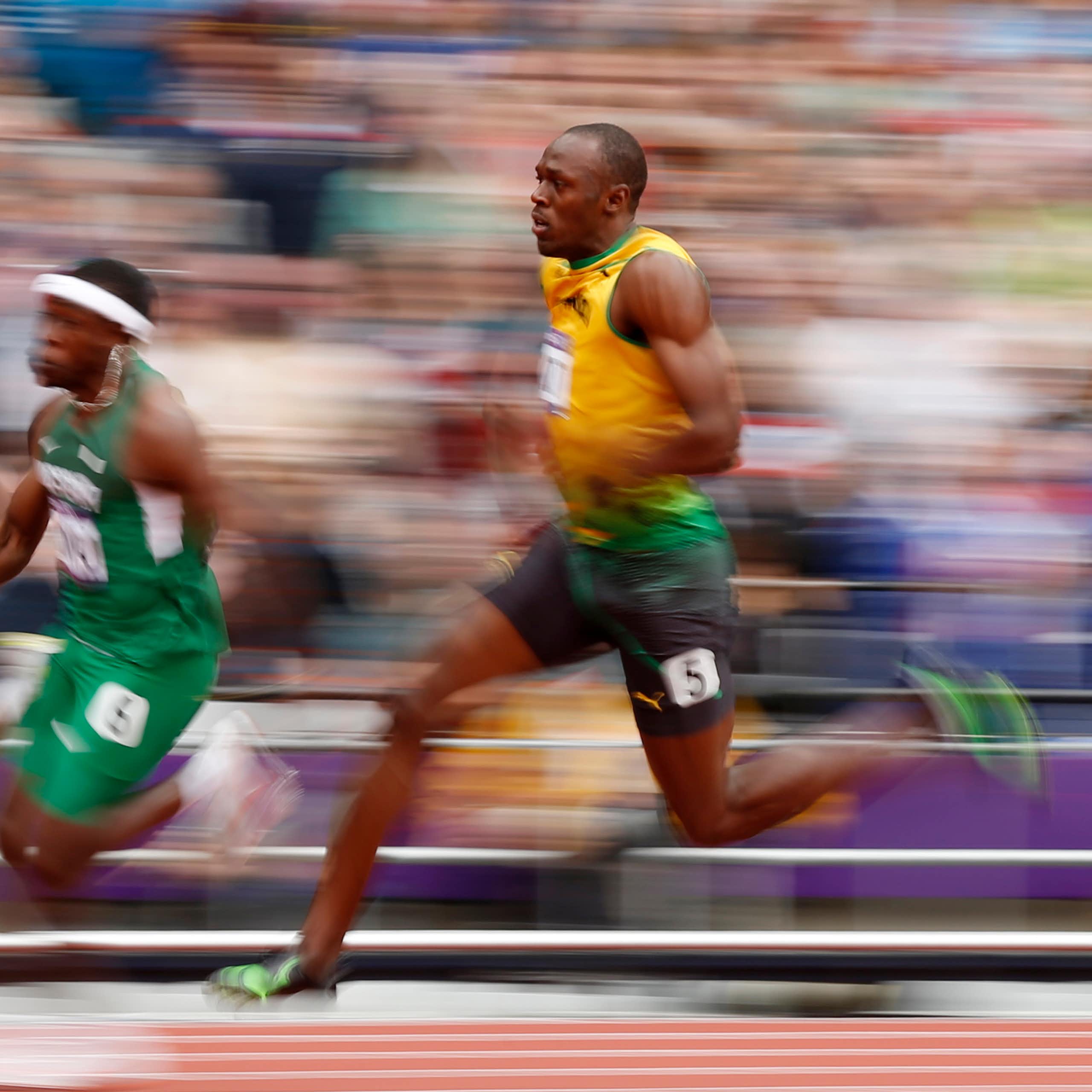Three Olympic sprinters running on track against blurred background.