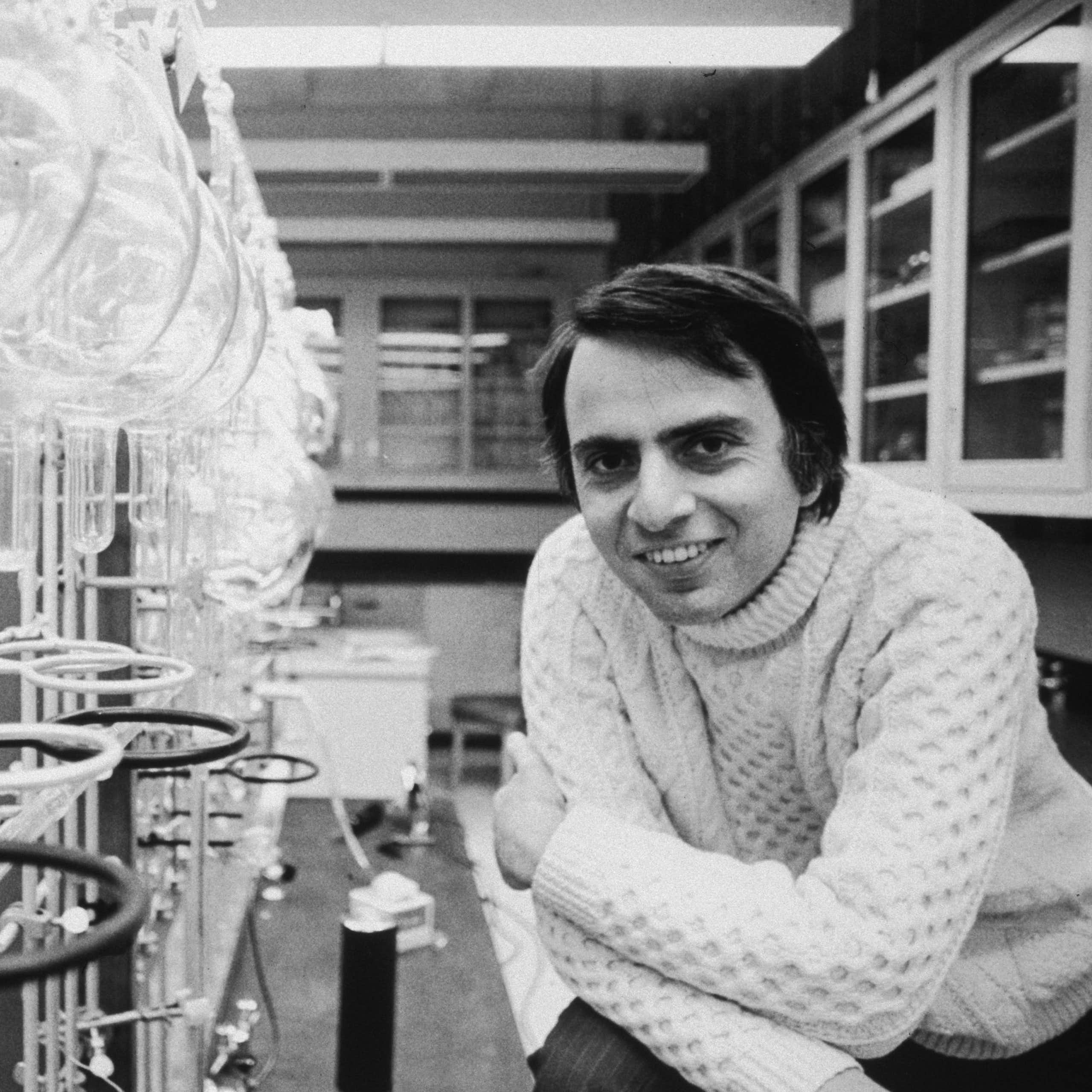 Uma fotografia em preto e branco de Carl Sagan em seu laboratório científico