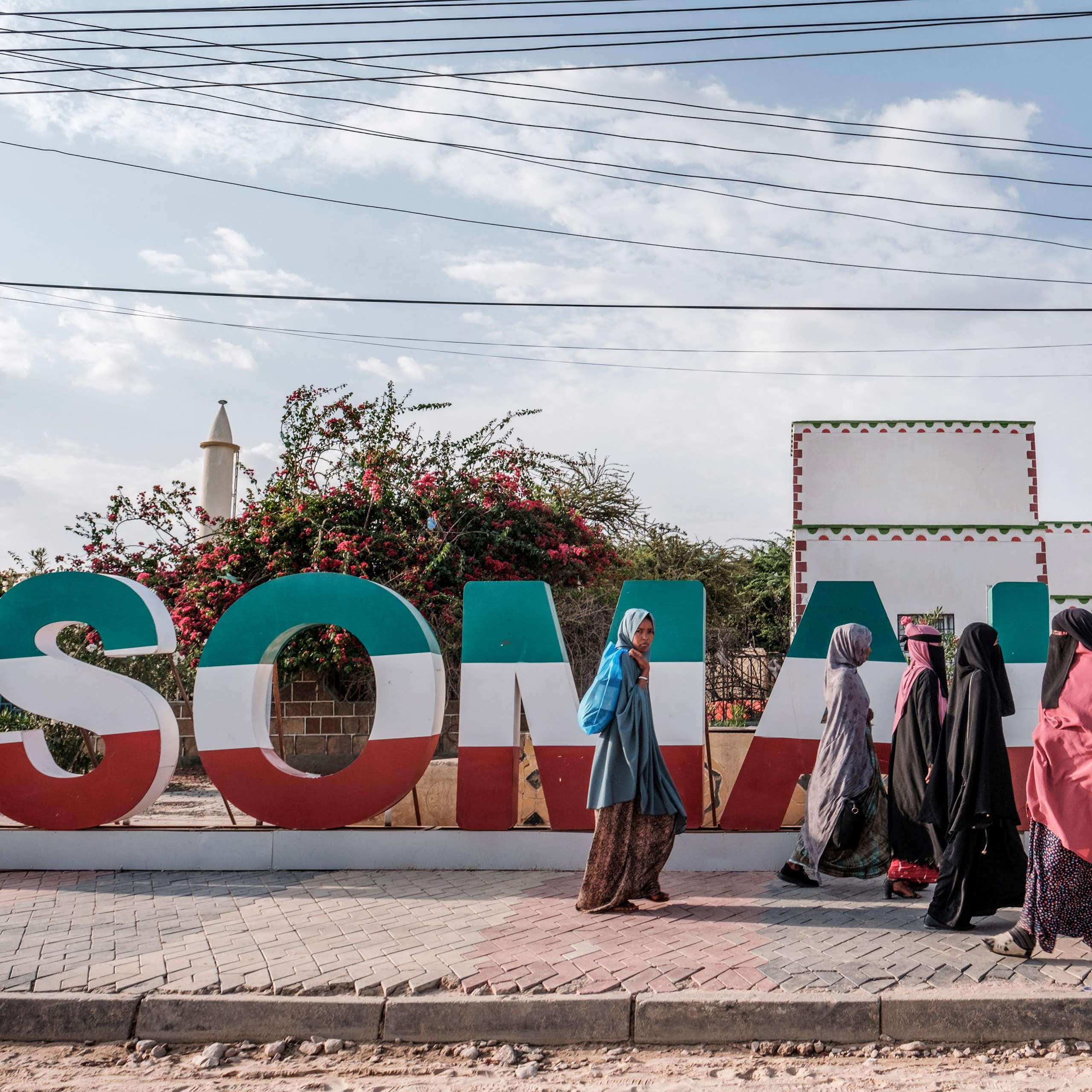 Women walking in front of Somaliland lettering in green, white and red