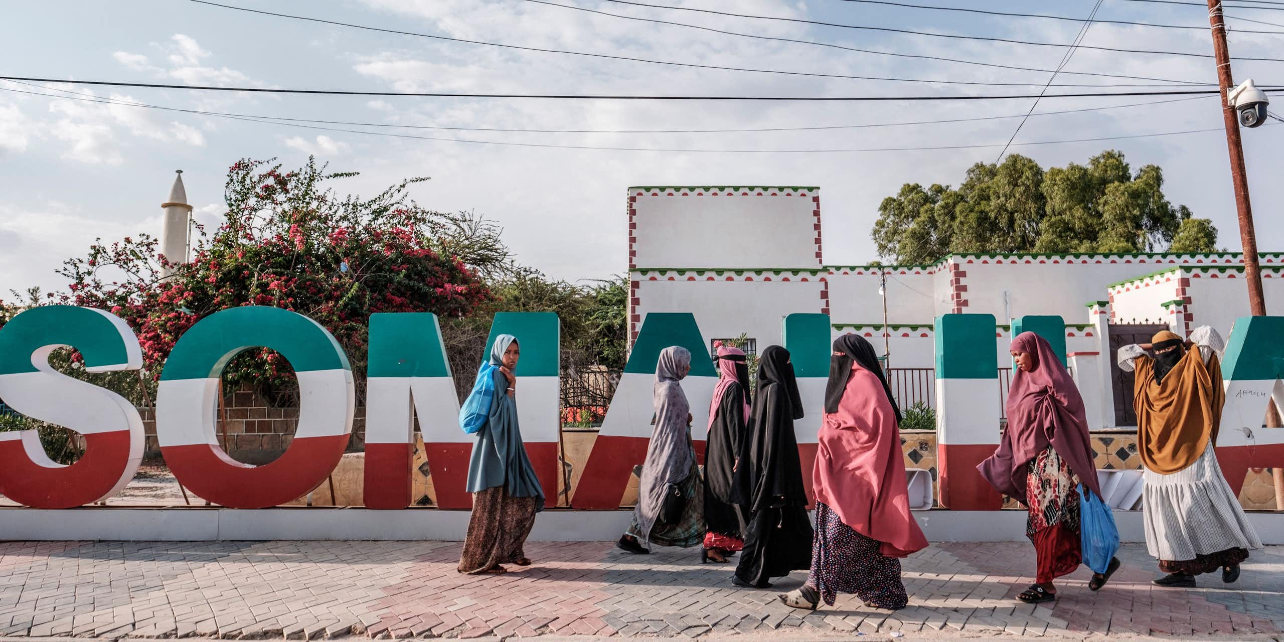 Women walking in front of Somaliland lettering in green, white and red