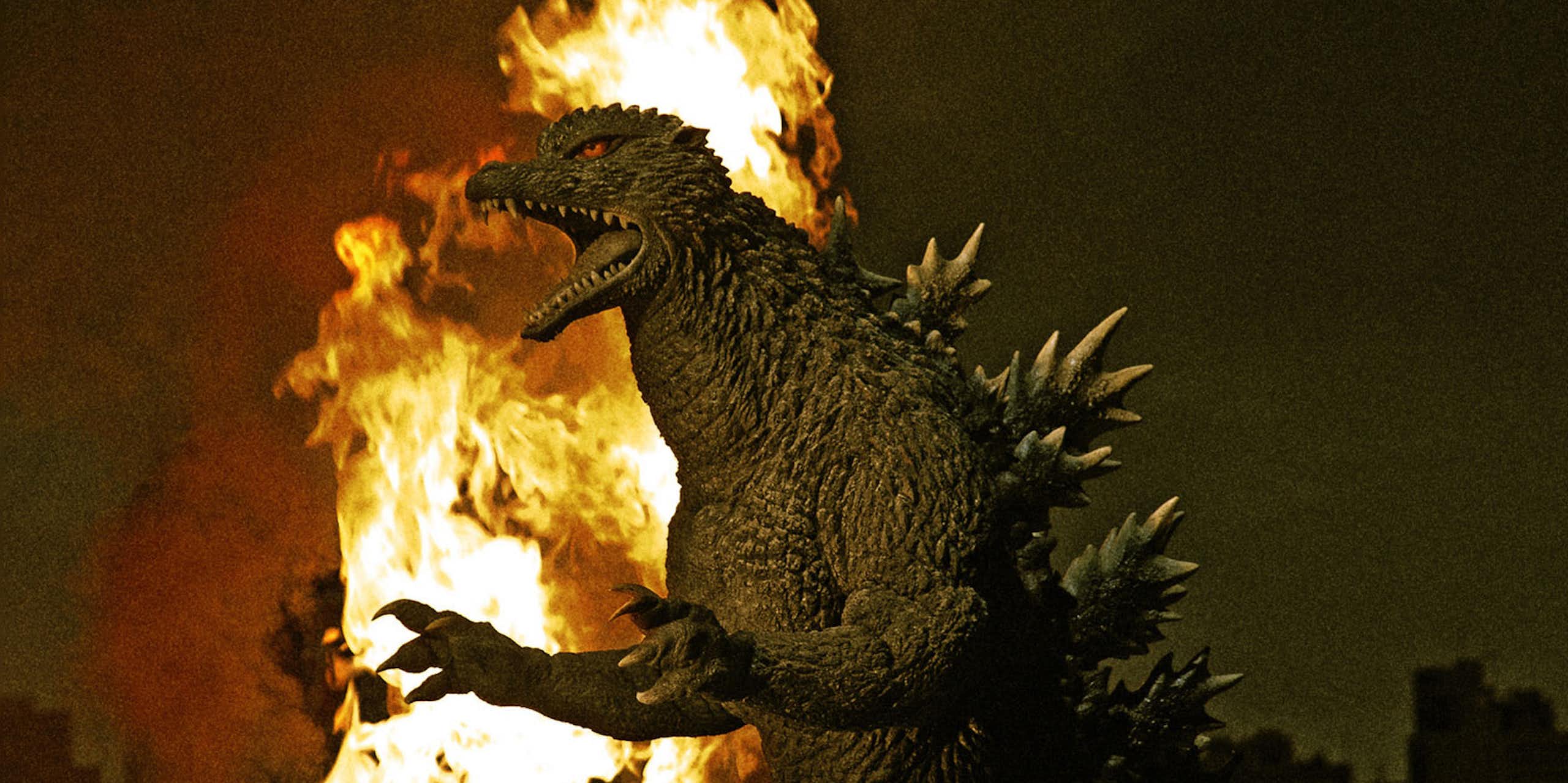 Godzilla with a burning city behind him
