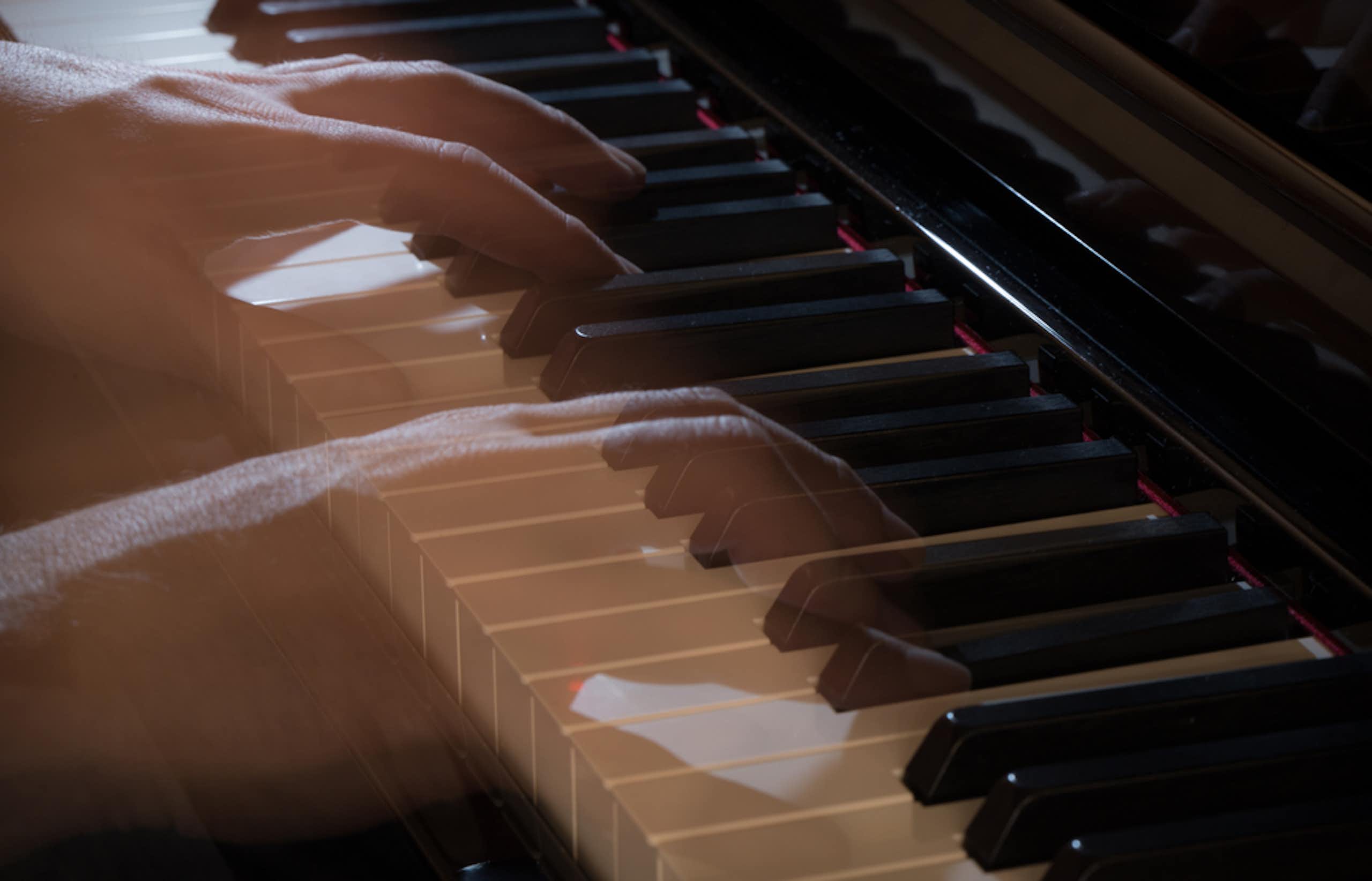 Mãos transparentes e fantasmagóricas tocam um piano.
