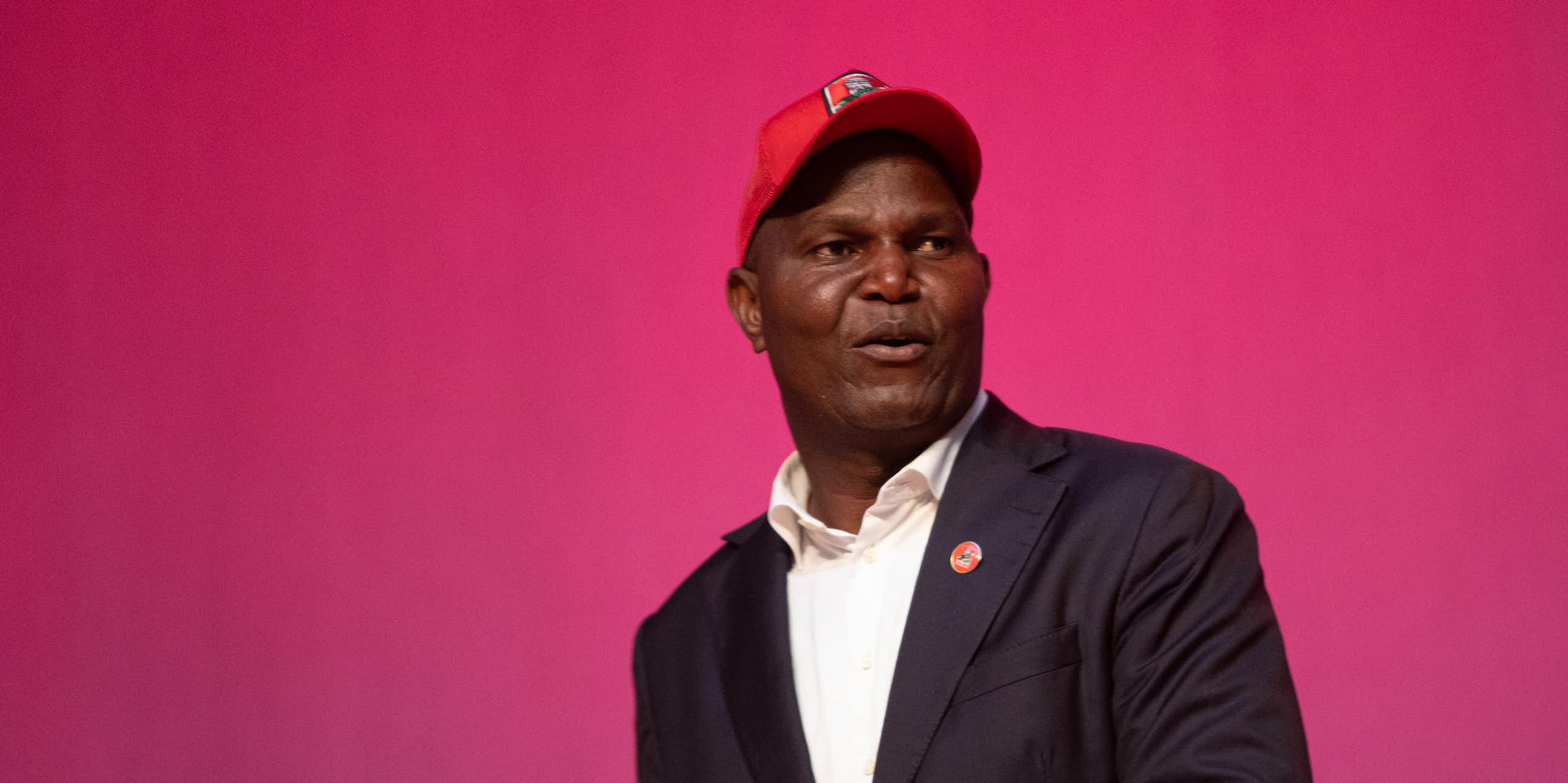  A man wearing a cap speaks to an audience.