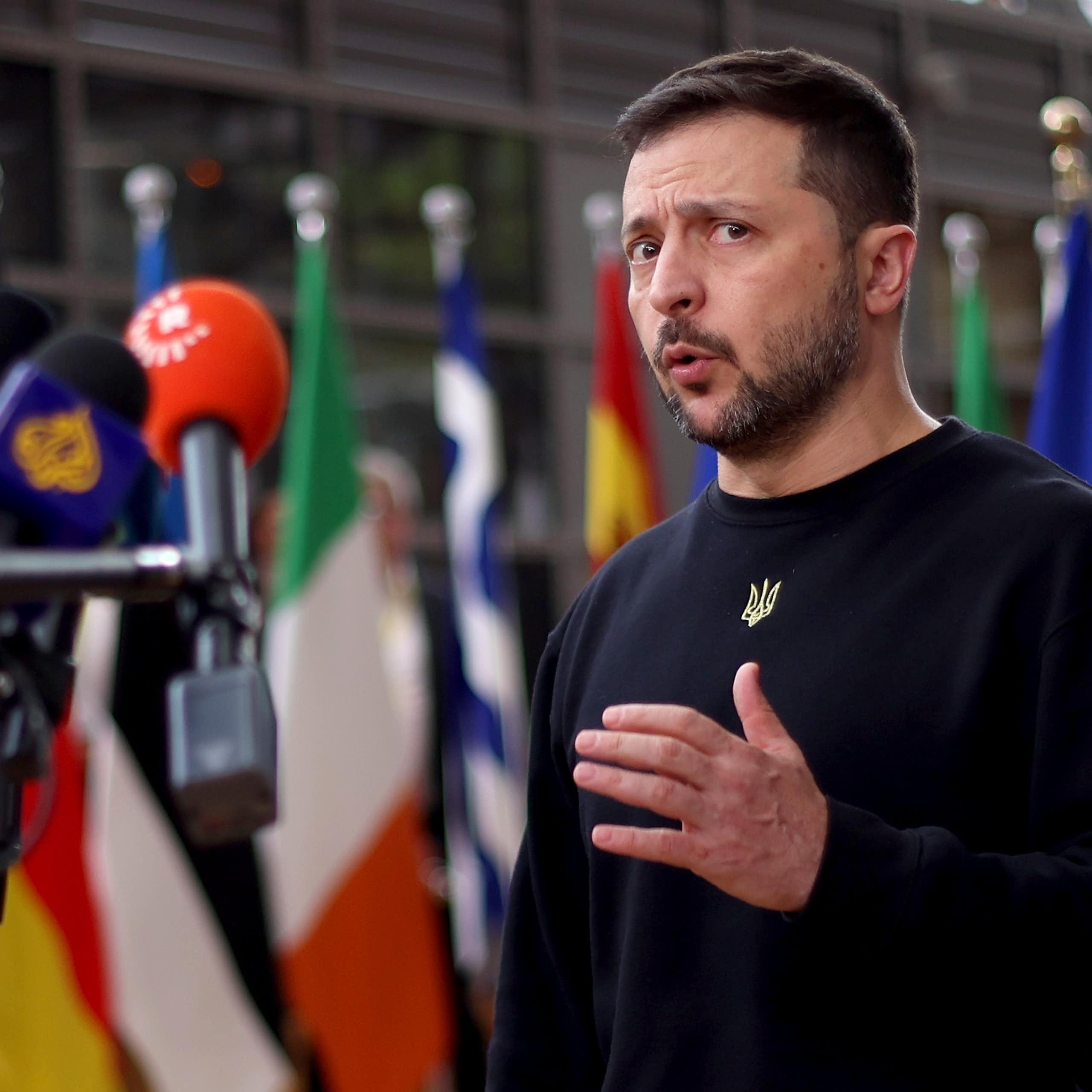 Volodymyr Zelensky talking into a bank of microphones.