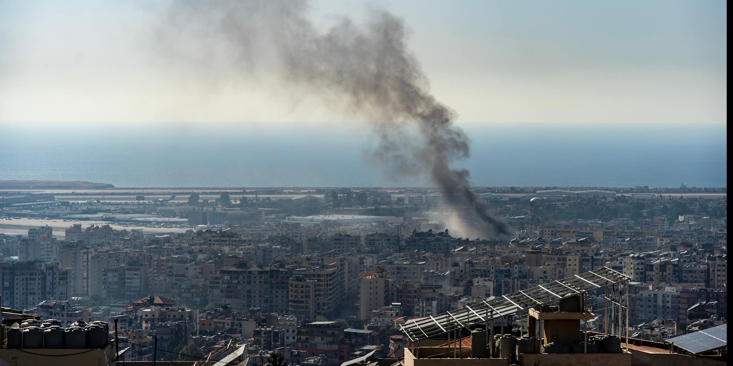 Vista de una ciudad de la que sale una columna de humo.