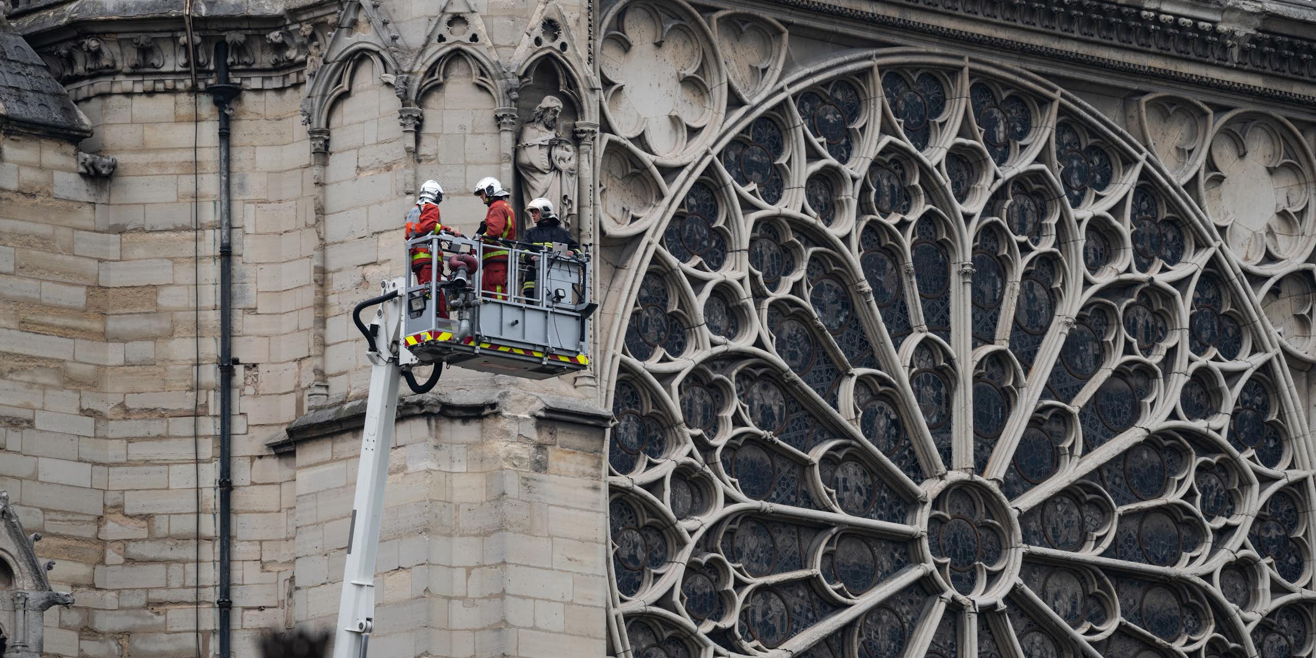 Un grupo de bomberos elevados al lado del rosetón de Notre Dame.