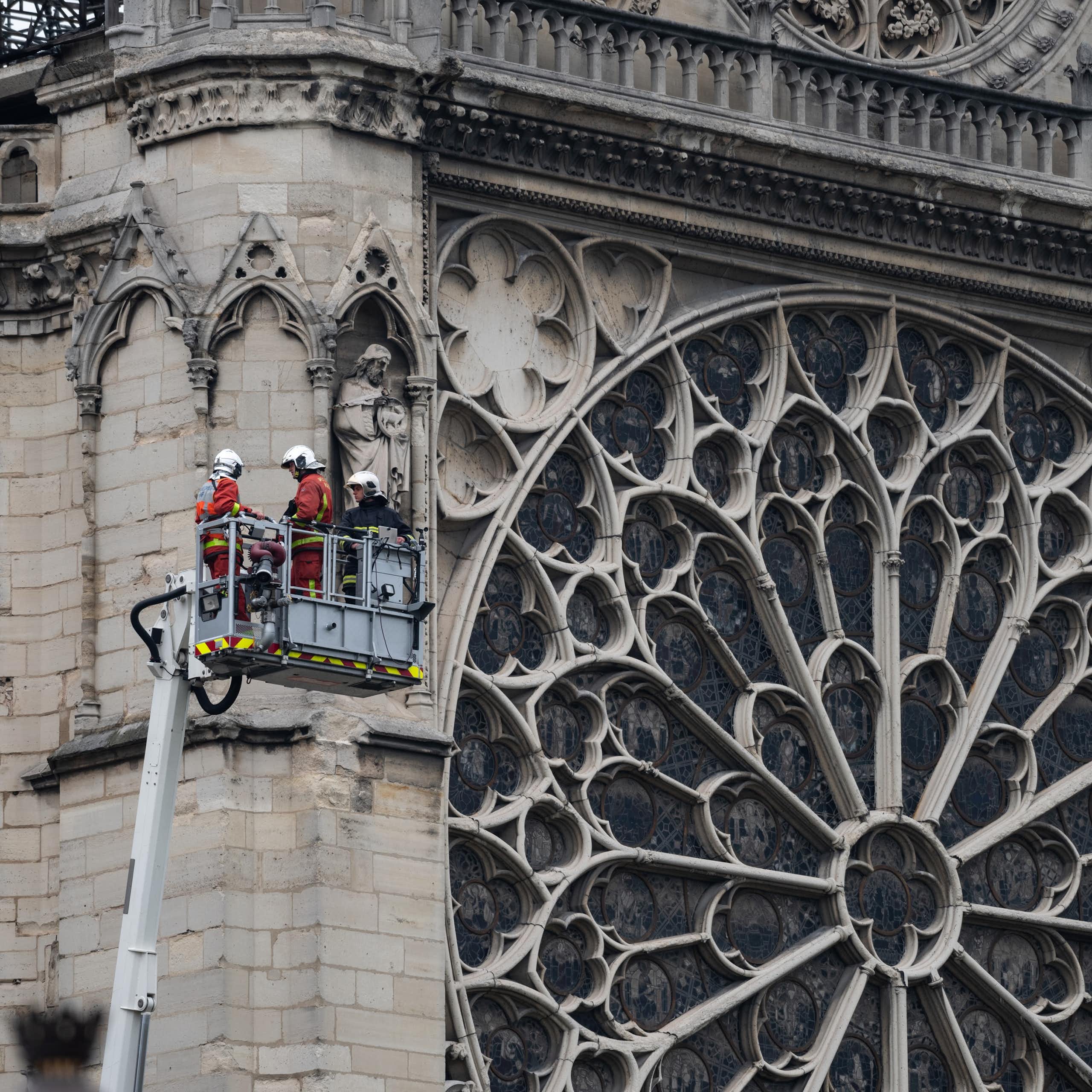 Un grupo de bomberos elevados al lado del rosetón de Notre Dame.