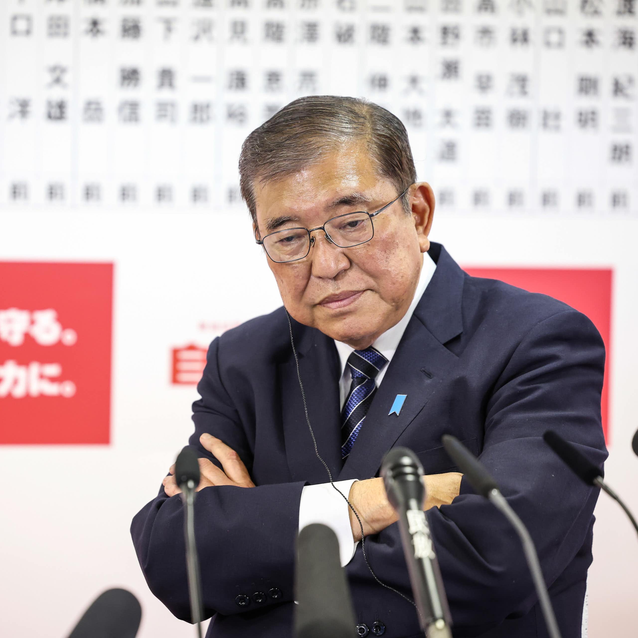 Shigeru Ishiba addressing the media with his arms crossed and a glum look on his face.