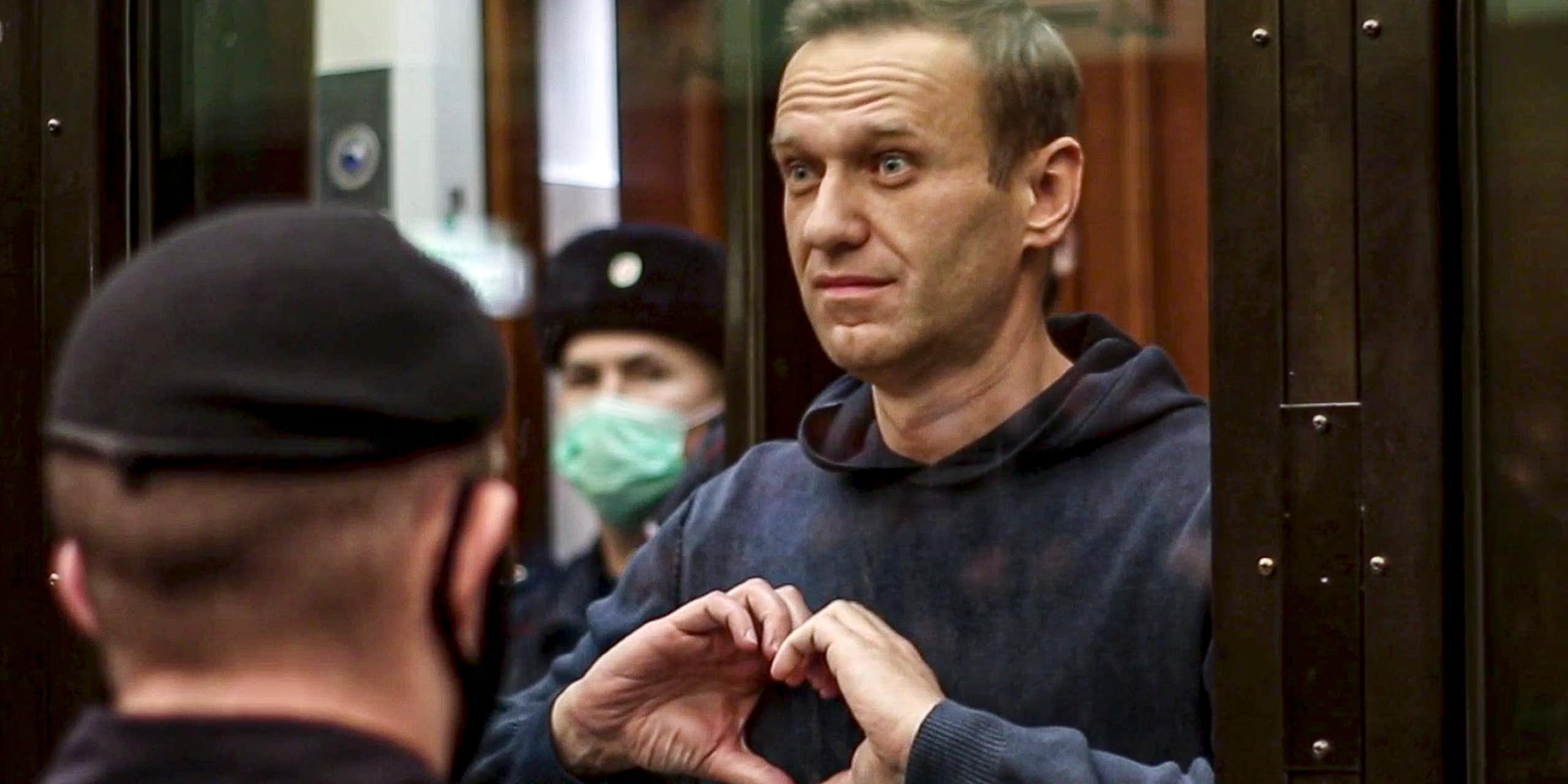 A man, Alexei Navalny, makes a heart-shaped symbol with his fingers.
