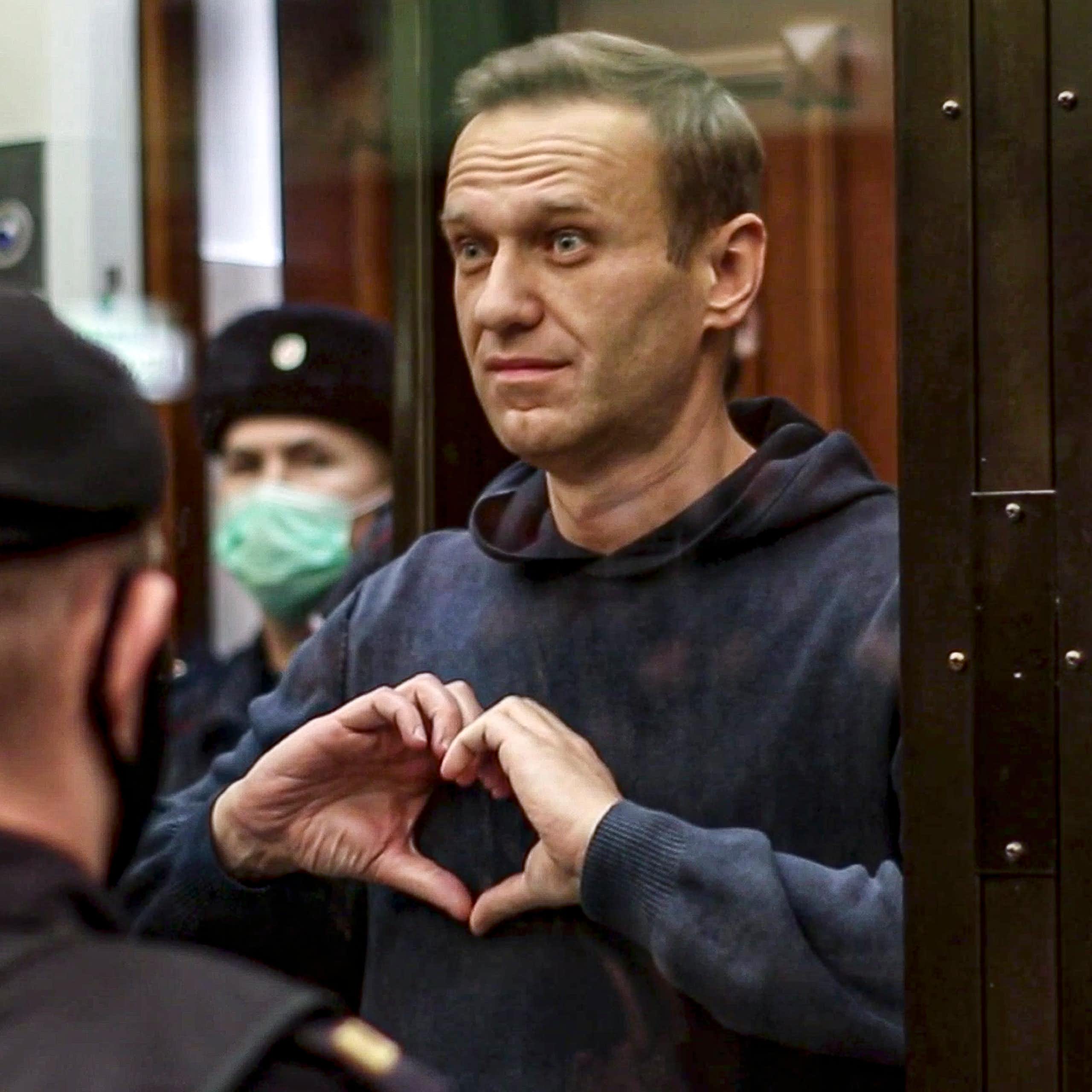 A man, Alexei Navalny, makes a heart-shaped symbol with his fingers.