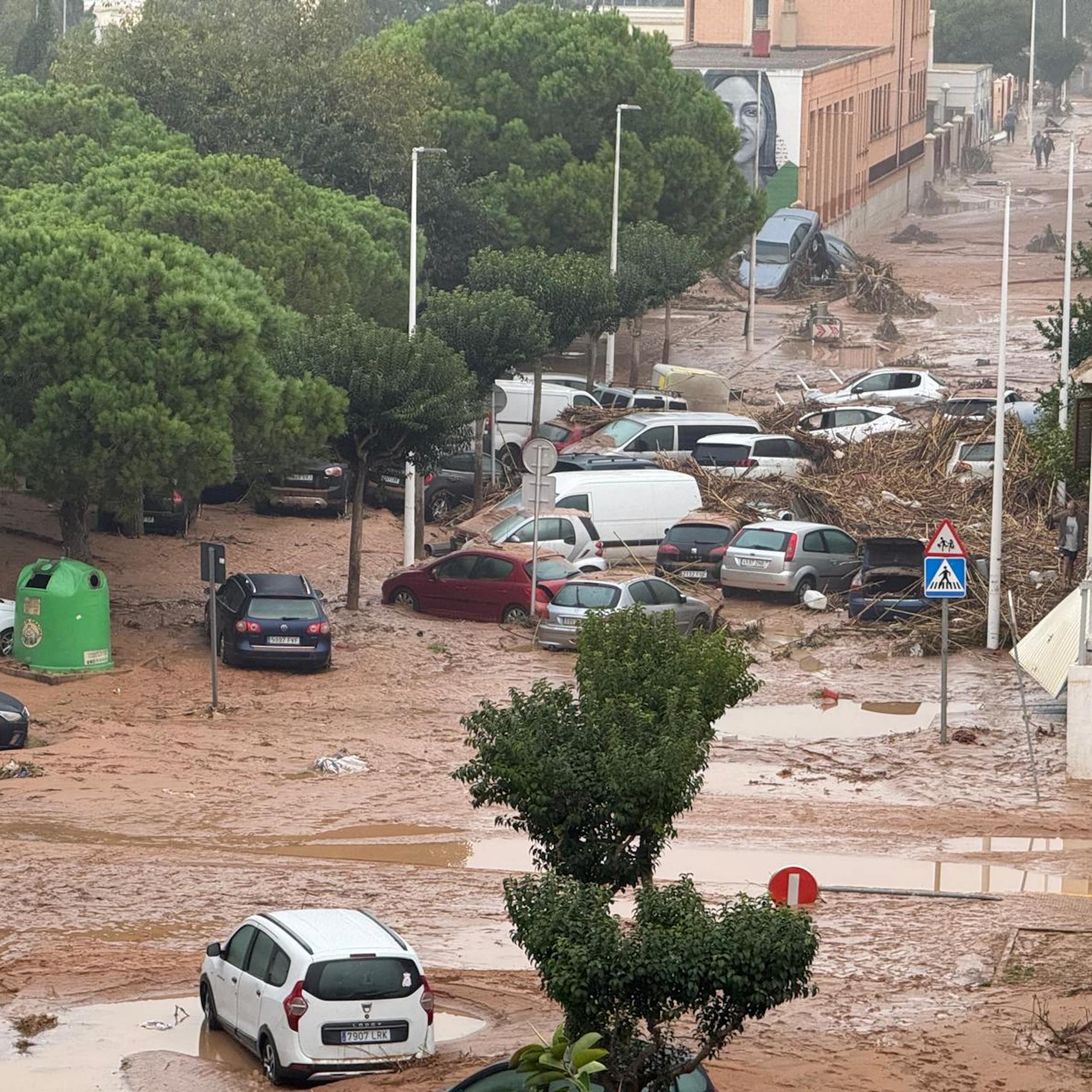 Coches situados caóticamente en una calle inundada de agua de color marrón