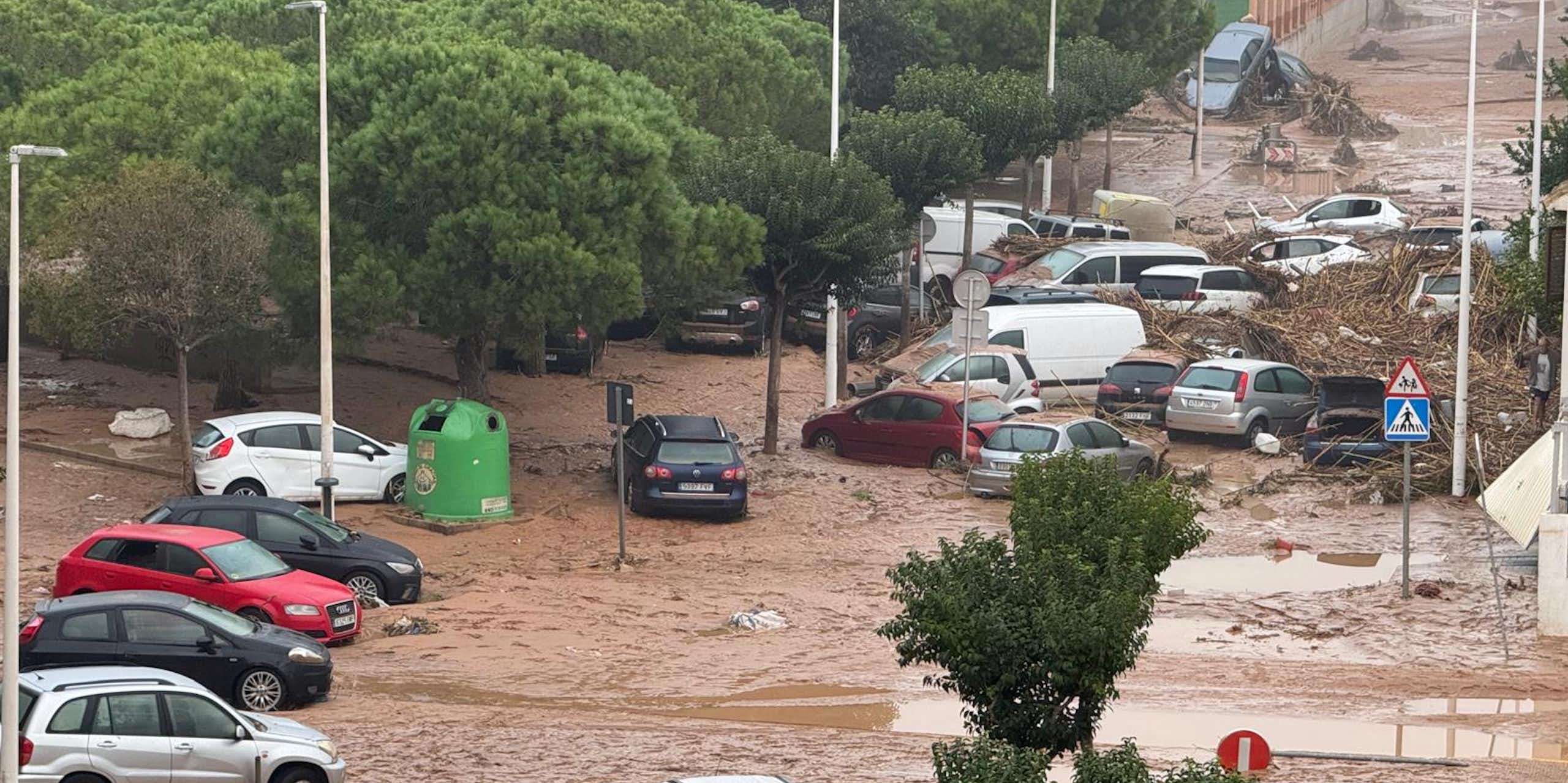 Coches situados caóticamente en una calle inundada de agua de color marrón