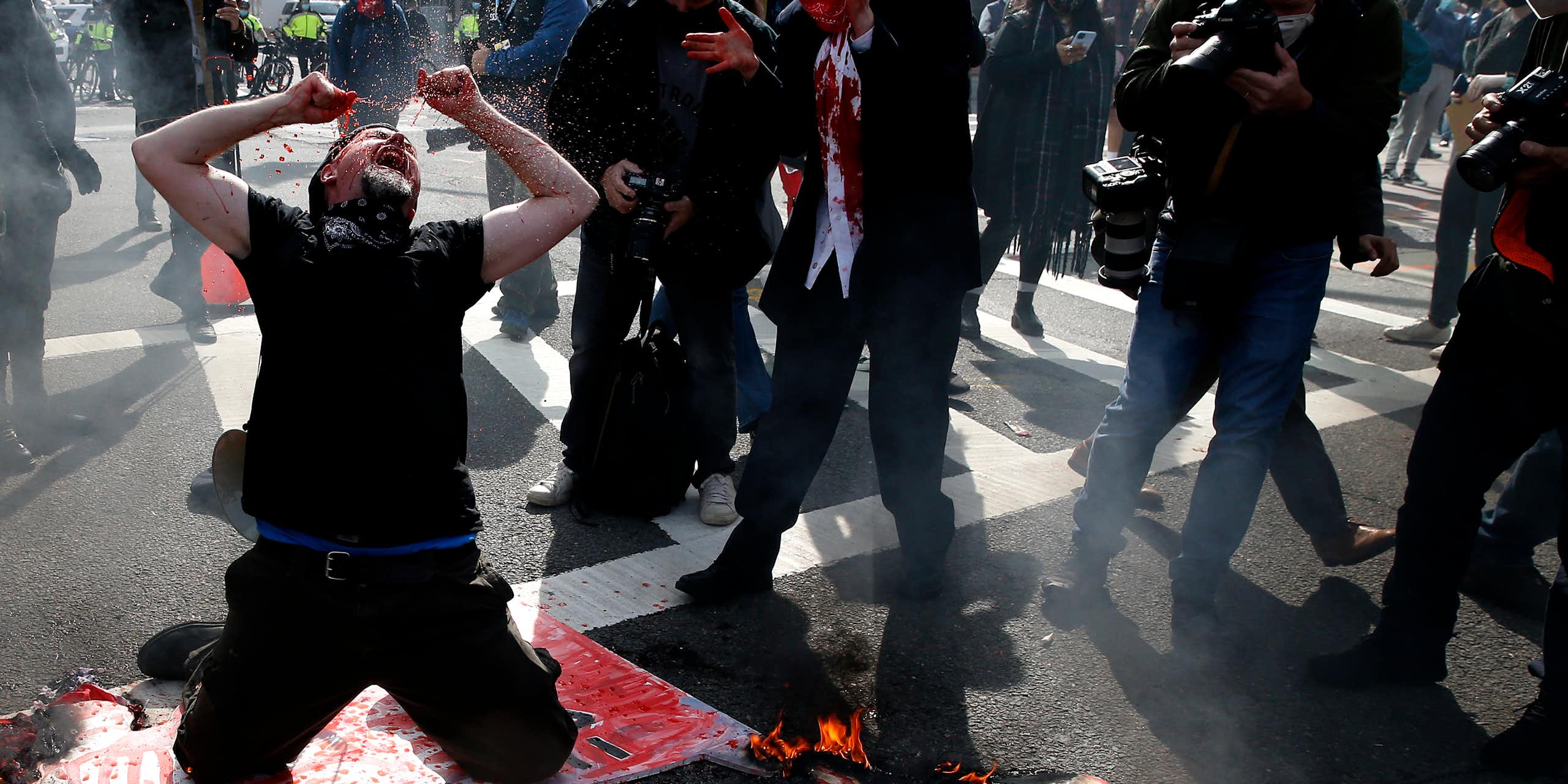 A protester dressed in black drops to his knees