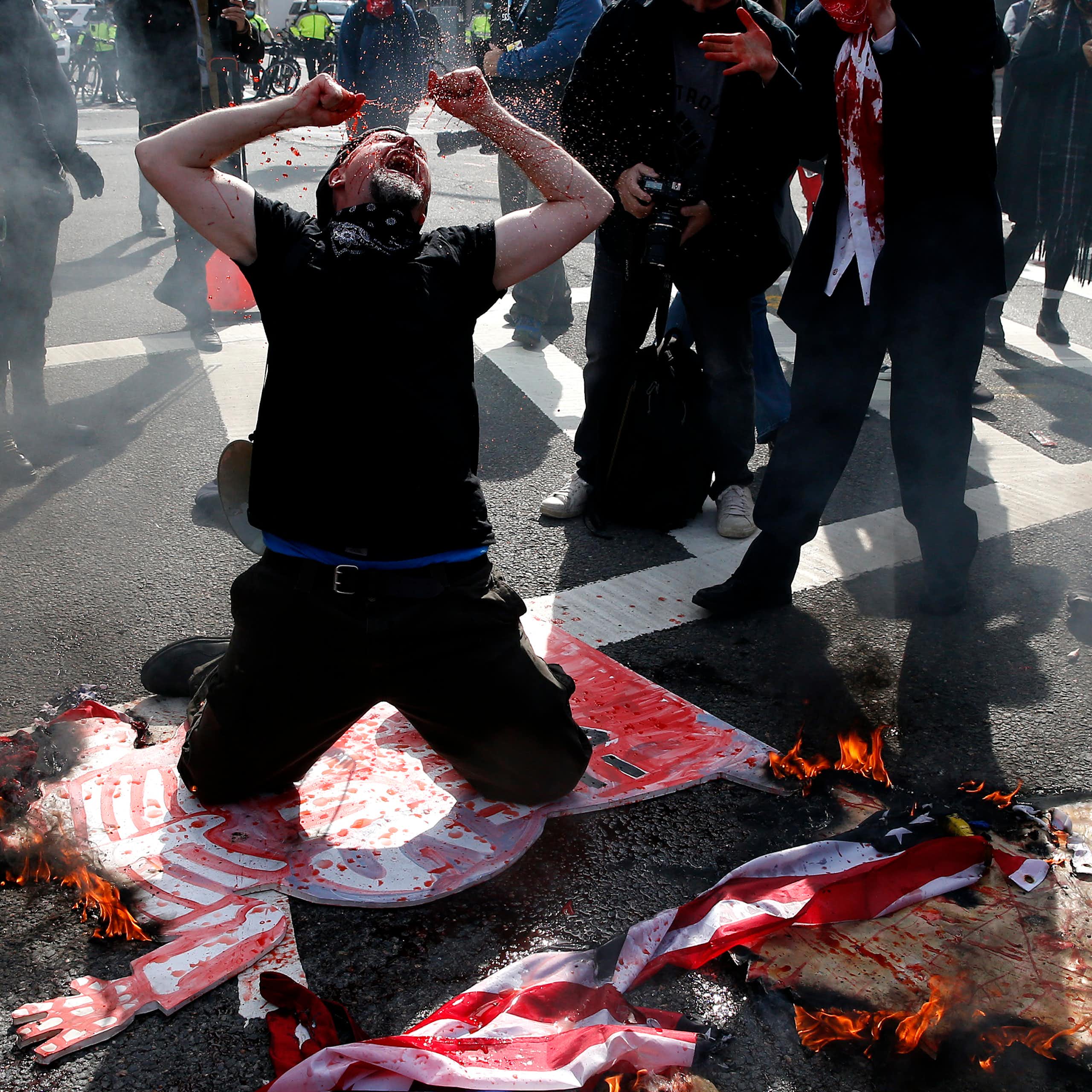 A protester dressed in black drops to his knees