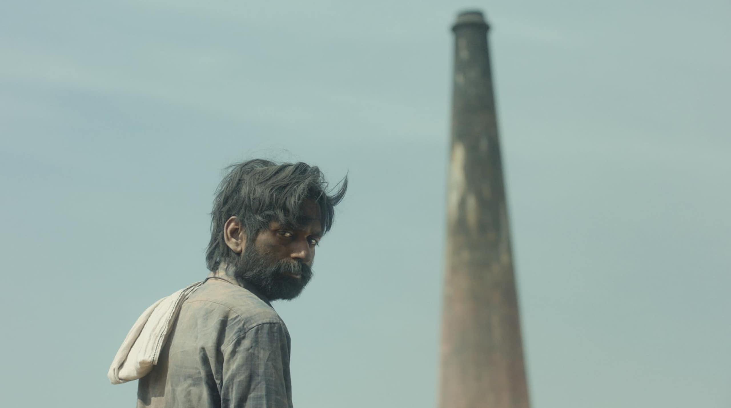 Man stands in front of a tall chimney