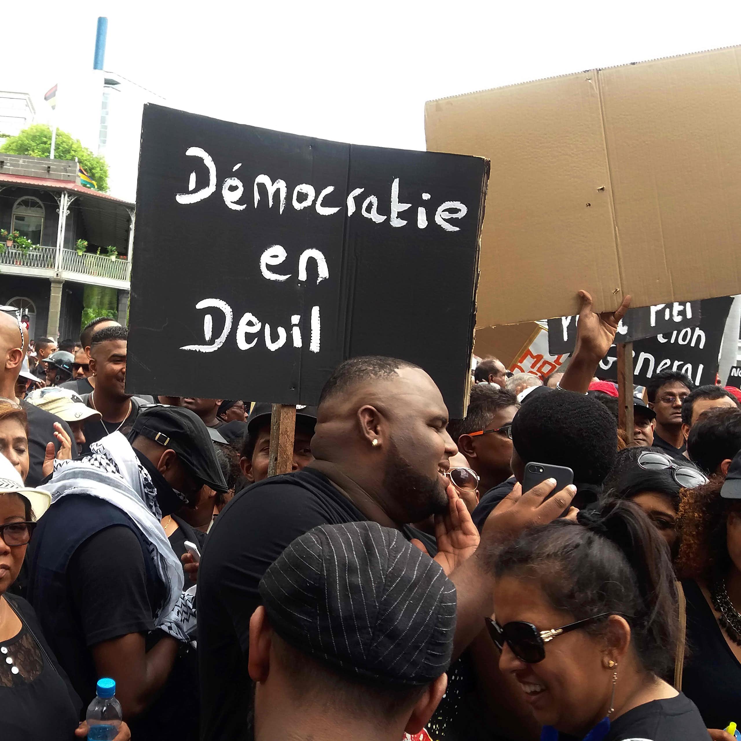 Protesters hold a placard reading 'Democracy in distress'