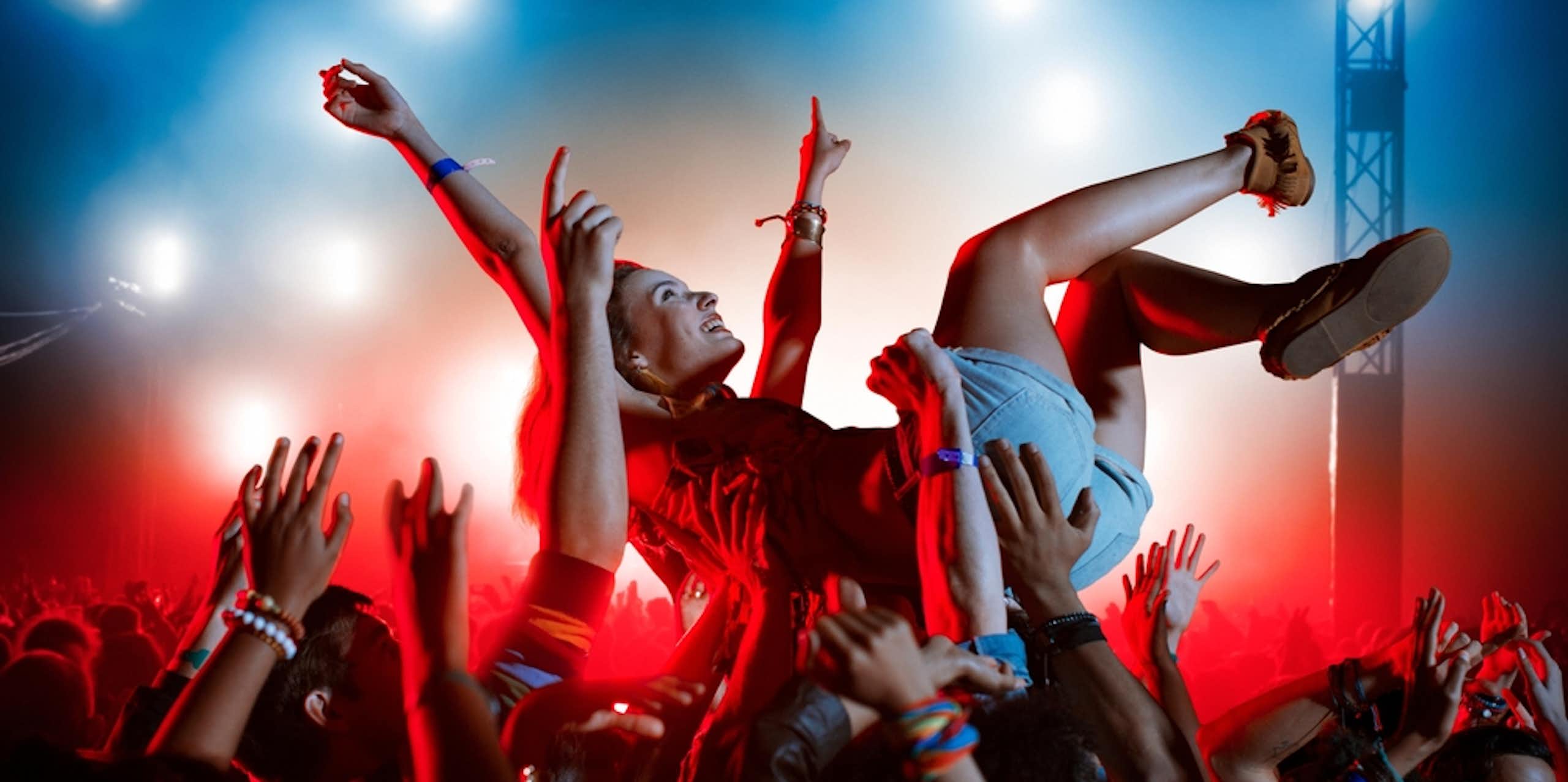 Young person crowd surfing at outdoor gig or music festival