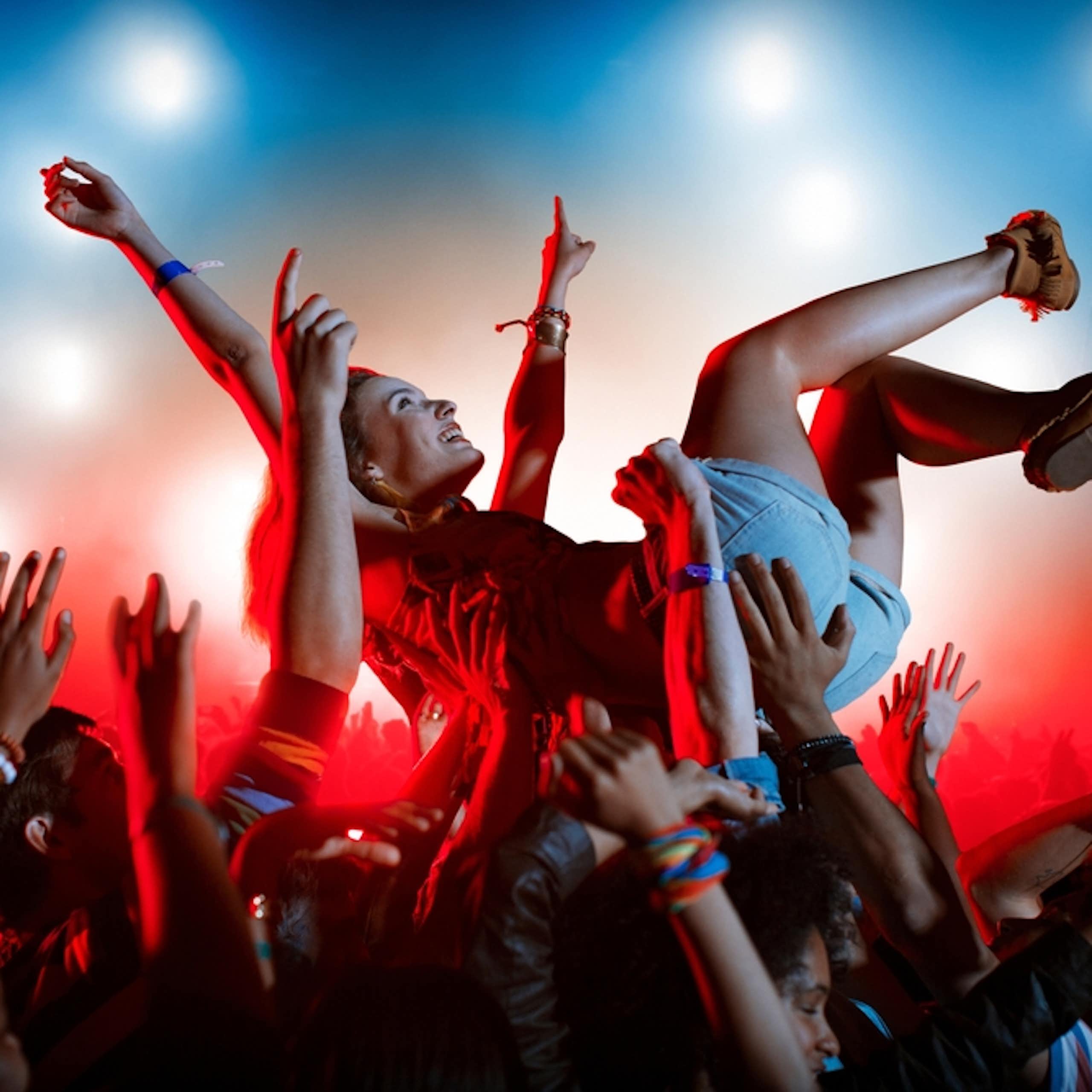 Young person crowd surfing at outdoor gig or music festival